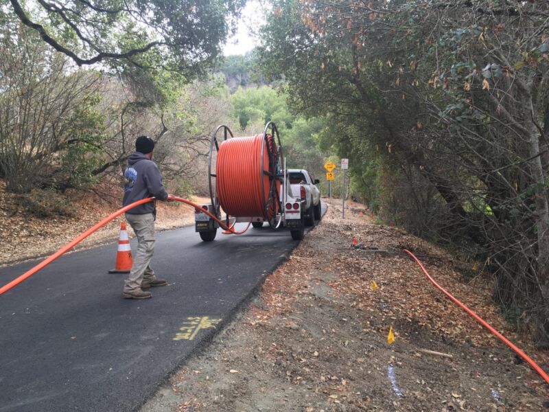 Un trabajador se prepara para instalar conductos de fibra desde un carrete grande.