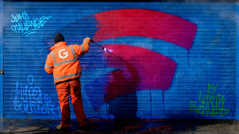 Man removing Stadia logo from a wall with high pressure water spray