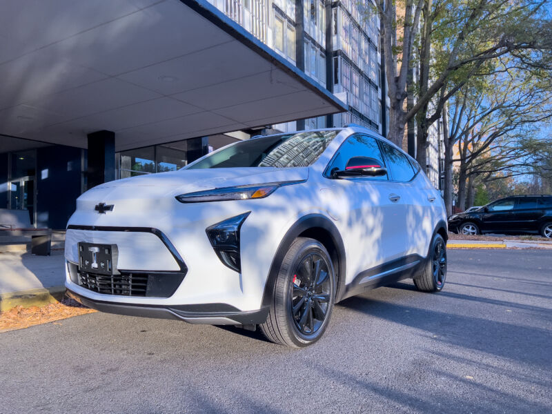 A white Bolt EUV parked outside a midcentury building