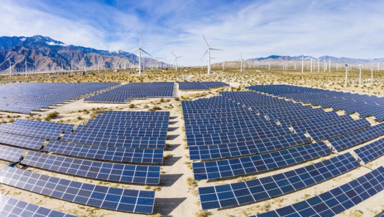 A field of solar panels and windmills in the desert.