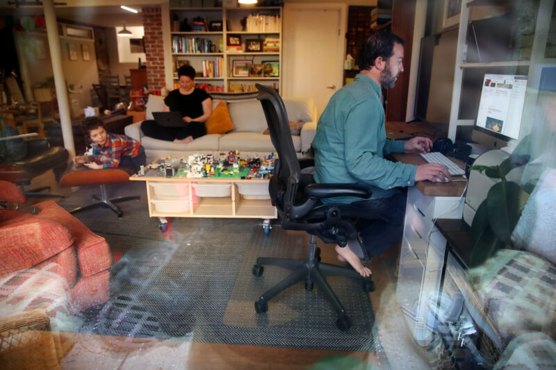 Parents work on their computers while their son entertains himself at their home in Boston in April 2020.