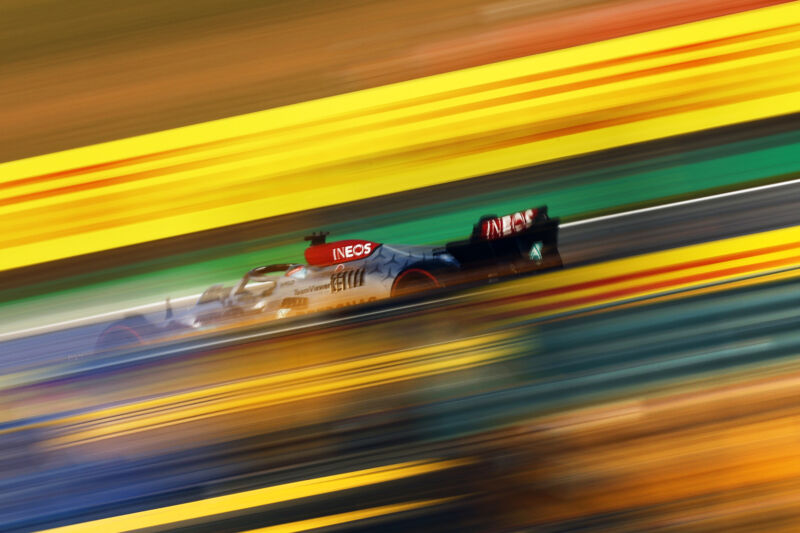 A colorful but blurry photo of George Russell's Mercedes F1 car at the 2022 Brazilian Grand Prix. The background is streaks of yellow and green