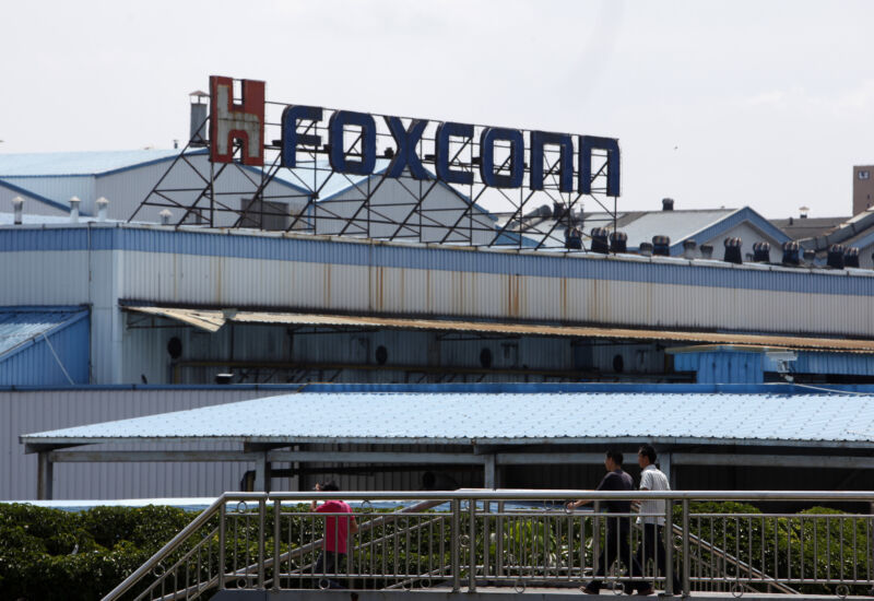 العمال امشي أمام مصنع Foxconn التابع لمجموعة Hon Hai Group في Shenzhen ، الصين ، في عام 2010. 