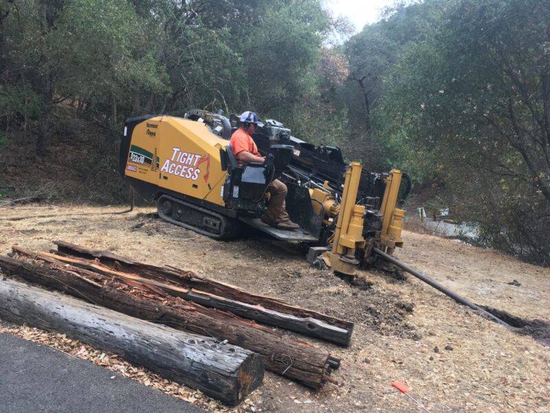 A man operates heavy machinery that installs fiber cables underground.