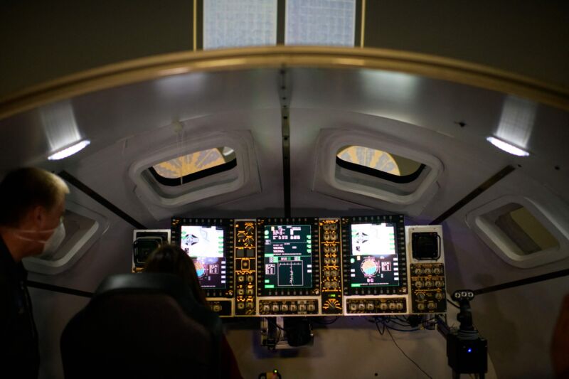 Las personas miran dentro de un simulador de la nave espacial Orion, que se utiliza para entrenar para acoplarse a la estación espacial Gateway, en las instalaciones del Simulador de Ingeniería de Sistemas del Centro Espacial Johnson en Houston.