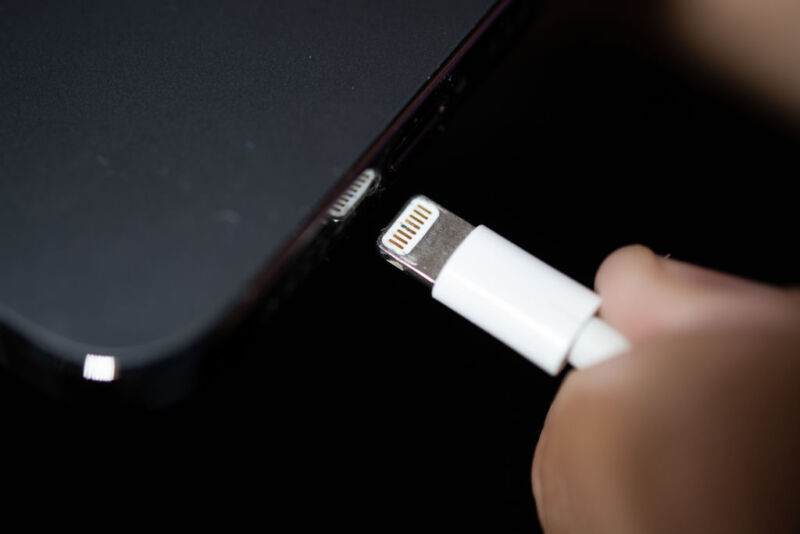 A Lightning charging plug is inserted into an Apple iPhone.