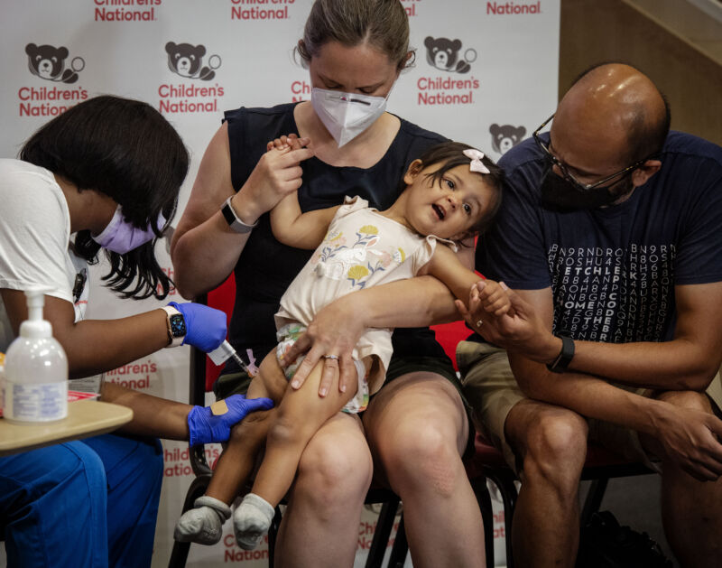 Reisa Lancaster RN, left, administers the Covid-19 vaccine to 14 month old Ada Hedge, center, being comforted by mom Sarah Close and dad Chinmay Hedge, right at  Children's National Research and Innovation Campus, in Washington, DC.