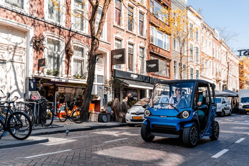 A solar-powered city car drives down a Dutch city street