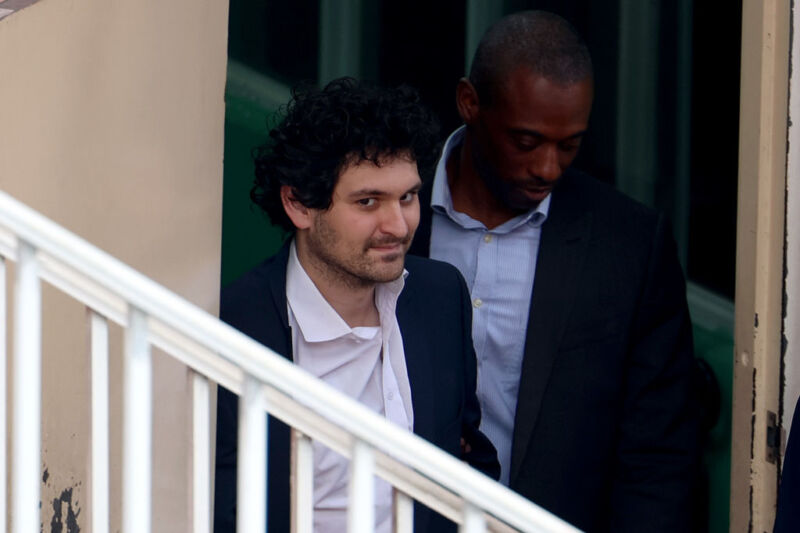 FTX co-founder Sam Bankman-Fried is escorted out of the Magistrate's Court on December 21, 2022 in Nassau, Bahamas.