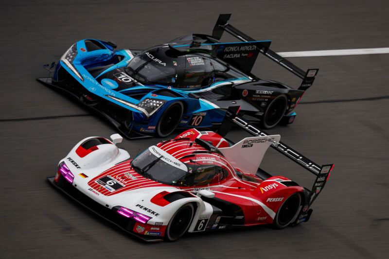 A pair of prototype race cars run side by side on the banking at Daytona