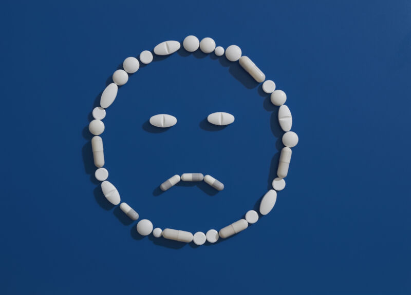 Image of a smiley face with a frown, with the lines drawn using pills.