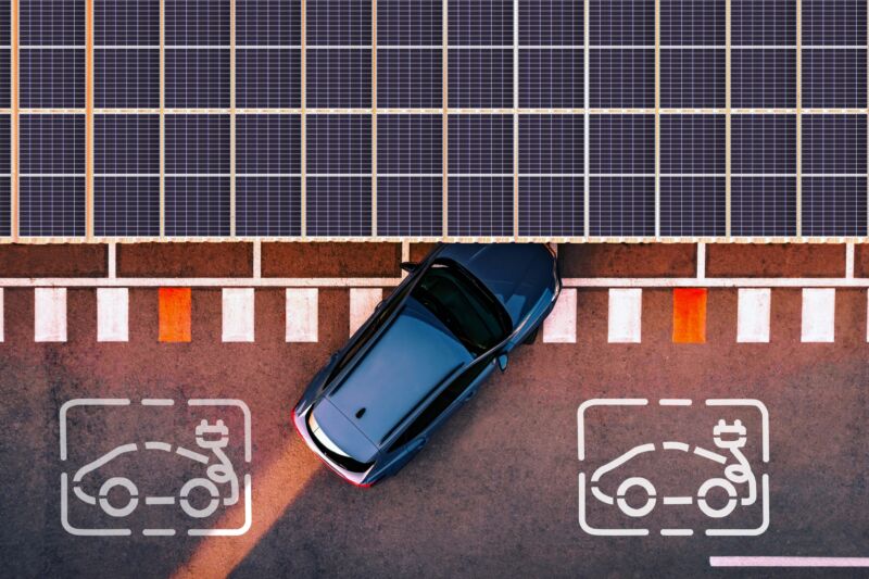 Direct overhead view taken with a drone of a charging station for electric and hybrid cars using solar panels to generate electricity to charge the cars battery while they are parked in the city