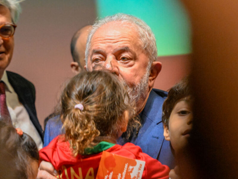 Brazilian President Luiz Inácio Lula da Silva kisses a child onstage at the end of a speech to supporters.
