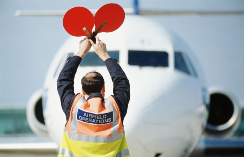 Operador de aeródromo señalando al avión