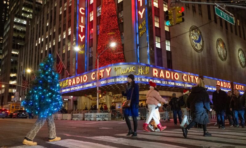 A man dressed as a Christmas tree walks near Radio City Music Hall on December 14, 2021 in New York City.
