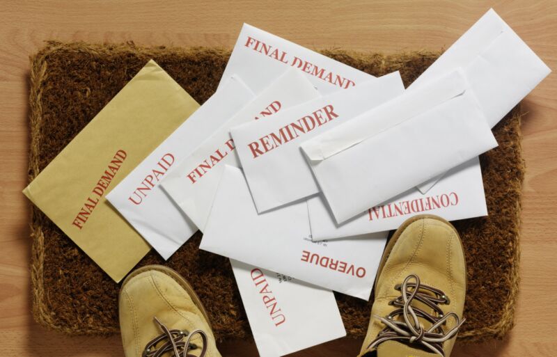 Envelopes with unpaid-bill notices laying on a doormat