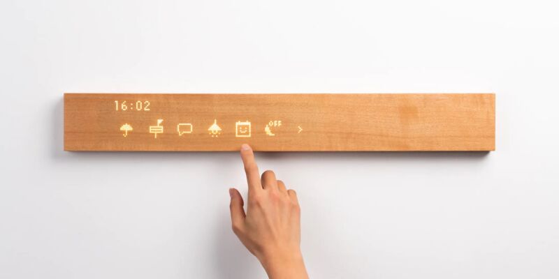 Placa de madera Mui en una pared, con íconos retroiluminados debajo para extender la mano