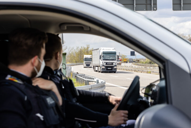 La policía alemana se sienta en su automóvil fuera de la autopista mientras observa el tráfico en movimiento