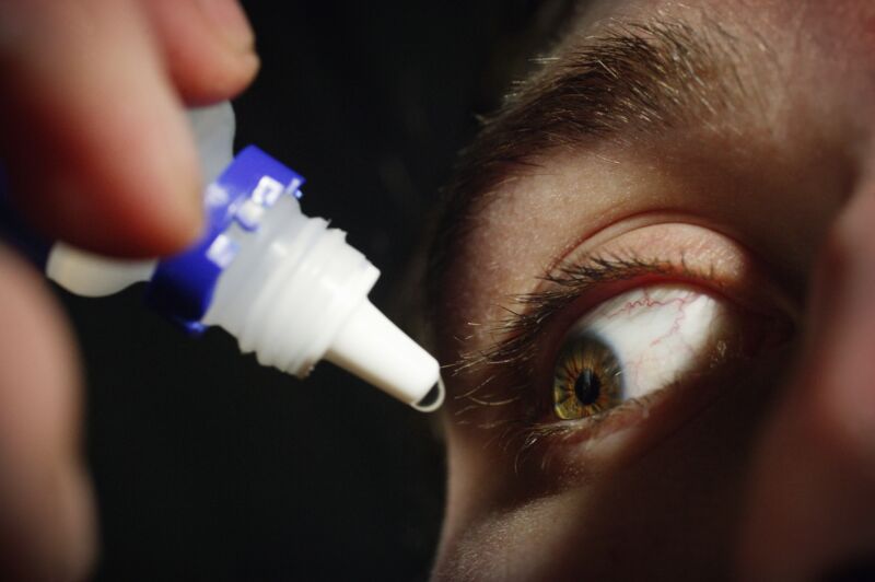 Young man applying eye drops.