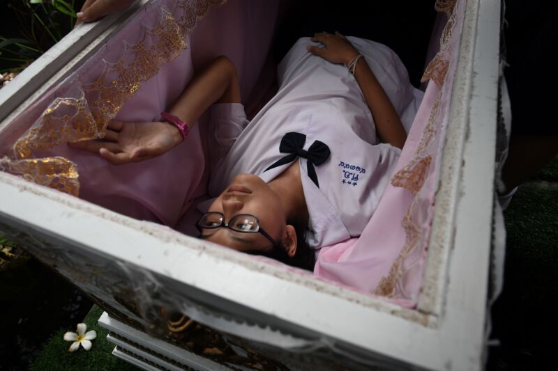 An alive Thai teenager fits inside a traditional coffin