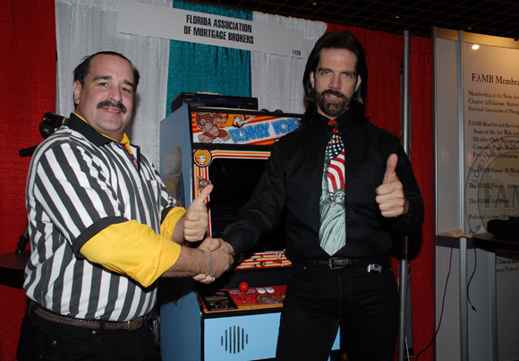 Mitchell (right) at the 2007 FAMB convention with former Twin Galaxies referee Todd Rogers and what appears to be a <em>Donkey Kong</em> cabinet with a modified joystick.