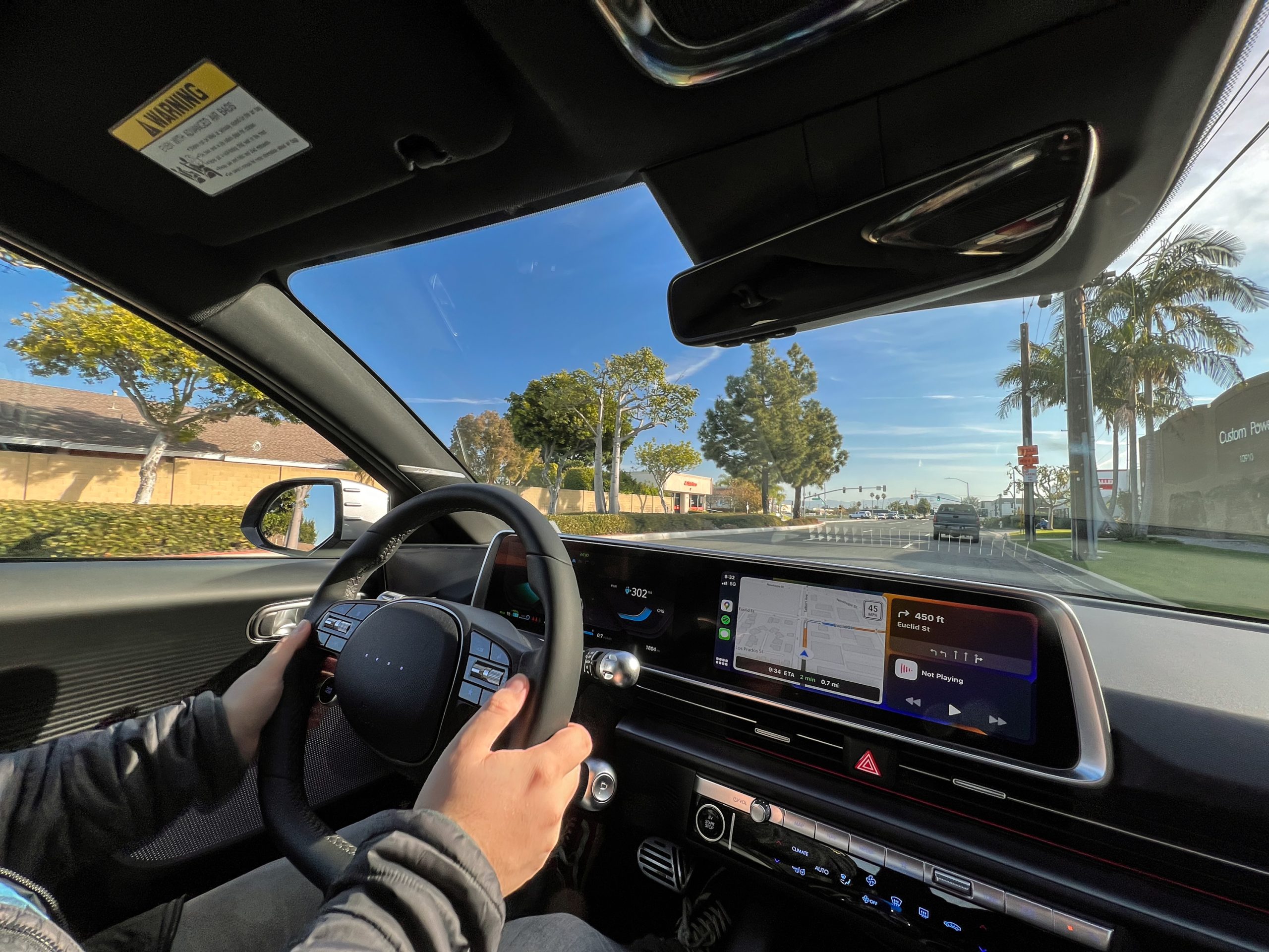 hands hold the steering wheel of an Hyundai Ioniq 6 as it drives down the road