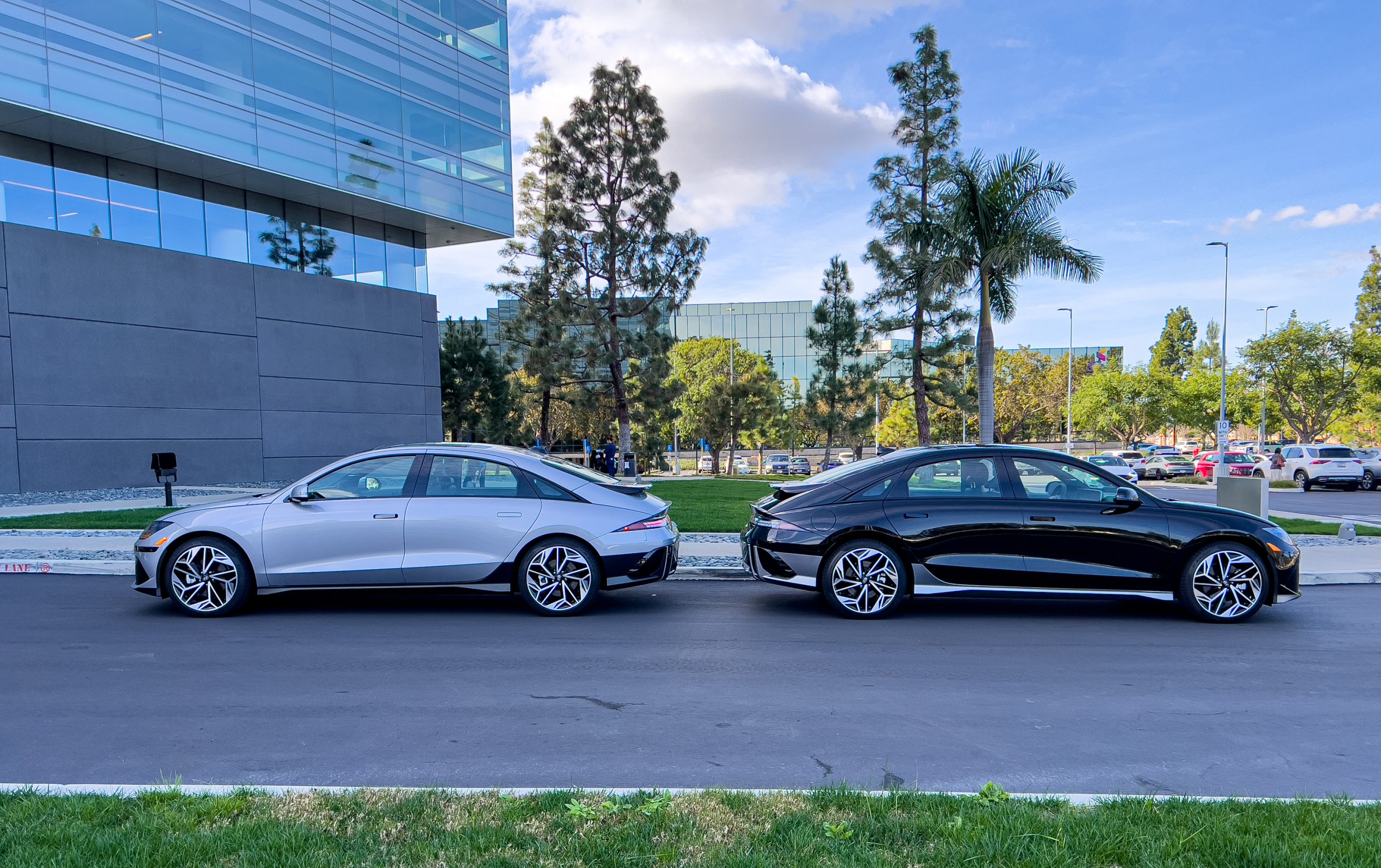 Two Hyundai Ioniq 6 EVs parked back to back with a couple of fir trees in the background