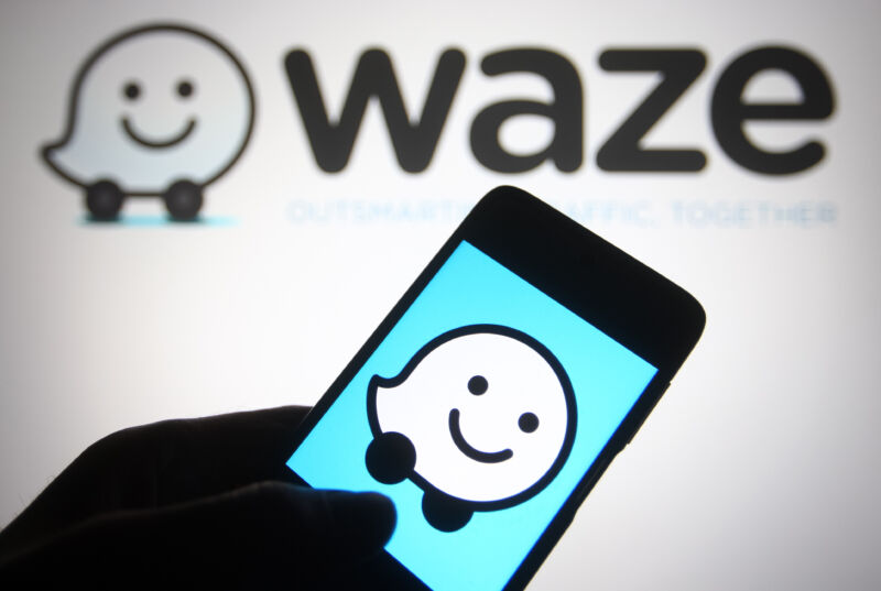 In this photo illustration a Waze logo of a GPS navigation software app is seen on a smartphone and a pc screen.