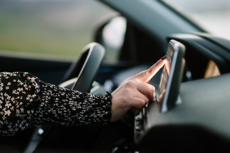 Detail of a woman touching with her finger a car's touch screen