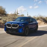 A blue BMW XM drives down a desert road