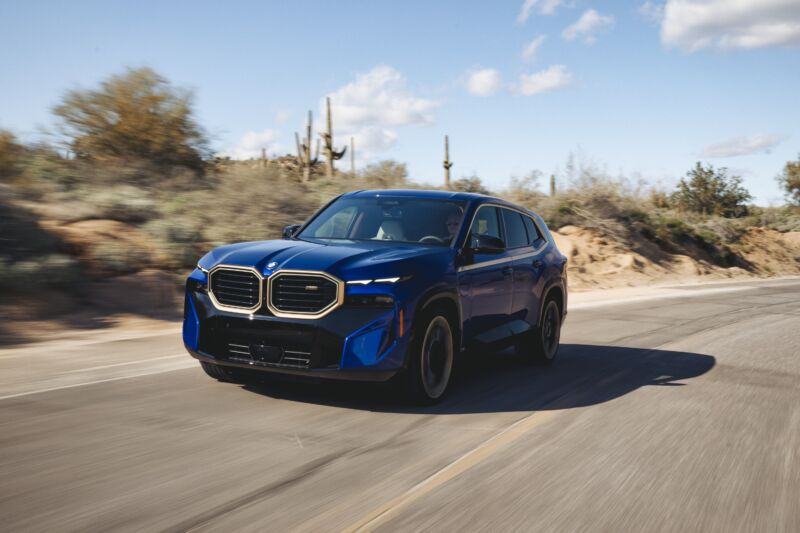 A blue BMW XM drives down a desert road