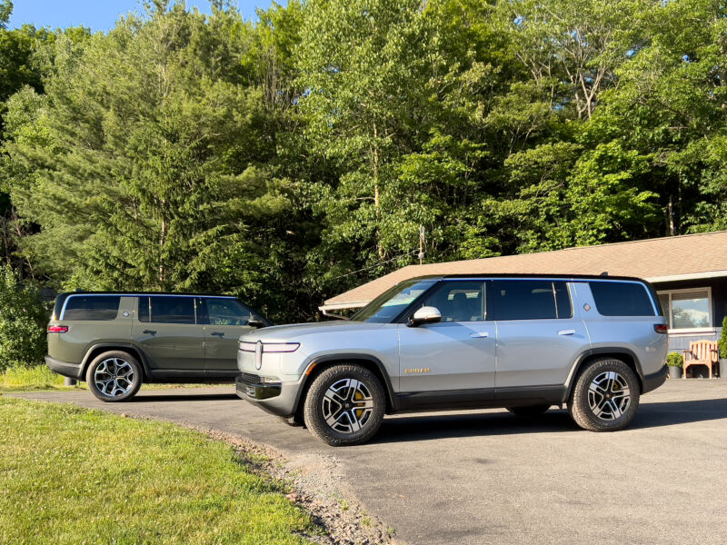 A pair of Rivian SUVs next to a motel