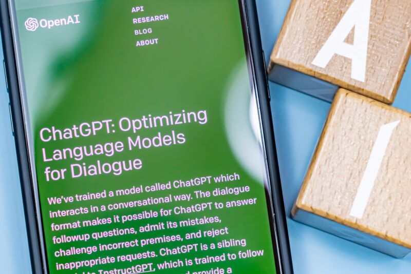 The ChatGPT website is displayed on a smartphone screen next to two blocks displaying the letters 