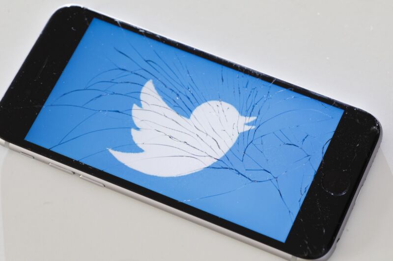 A Twitter logo on a phone with a shattered screen.