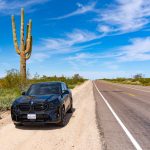 A BMW XM next to a very large Saguro cactus