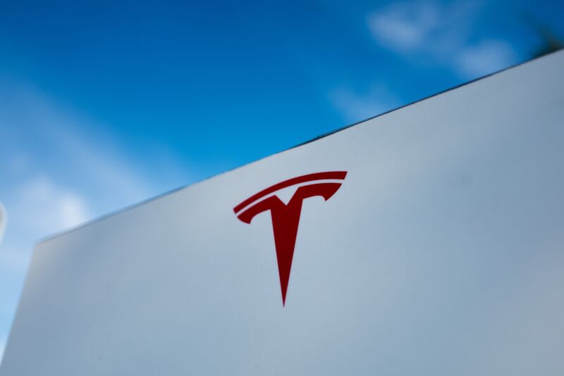 Close-up of Tesla Motors logo against a bright blue sky in Pleasanton, California, 2018