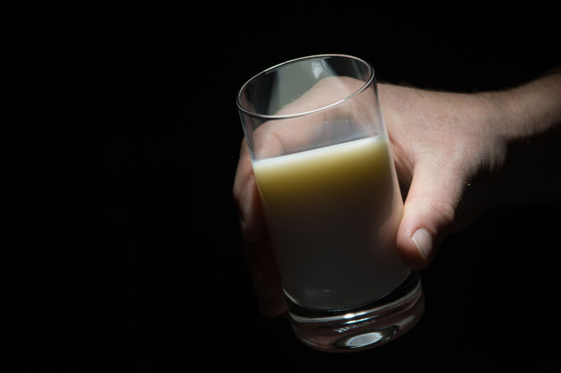 A hand holding a glass of milk.