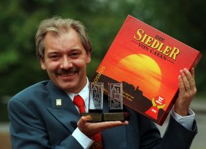 Klaus Teuber, holding an early version of Catan and his Spiel des Jahres awards in 1995.