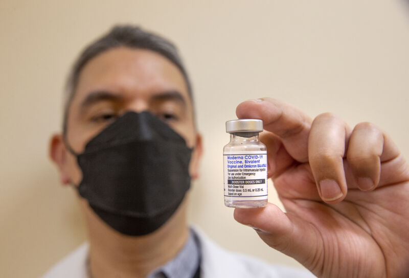A pharmacist holds a bottle containing Moderna's bivalent COVID-19 vaccine.