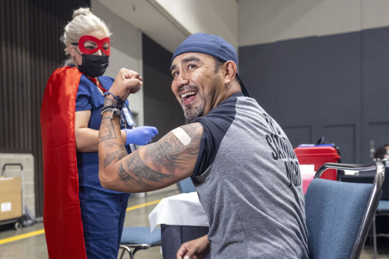 Miguel Torres flexes after Los Angeles County Department of Public Health nurse Yessica Carrillo gave him a COVID-19 booster during the Los Angeles Comic Con.