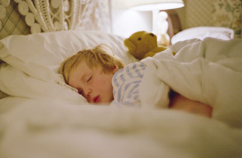 Young boy sleeping in a bed.