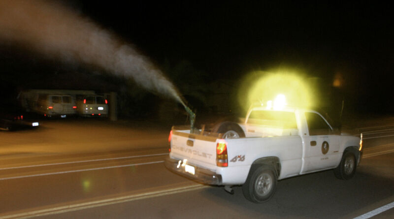 Eddie Robles conduce un camión de nebulización de control de vectores del condado de Maricopa a través de un vecindario en Tempe, Arizona, 4 de agosto de 2004. Las áreas conocidas por tener altas poblaciones de mosquitos se empañan por la noche para matar el insecto y ayudar a prevenir la propagación del virus del Nilo Occidental