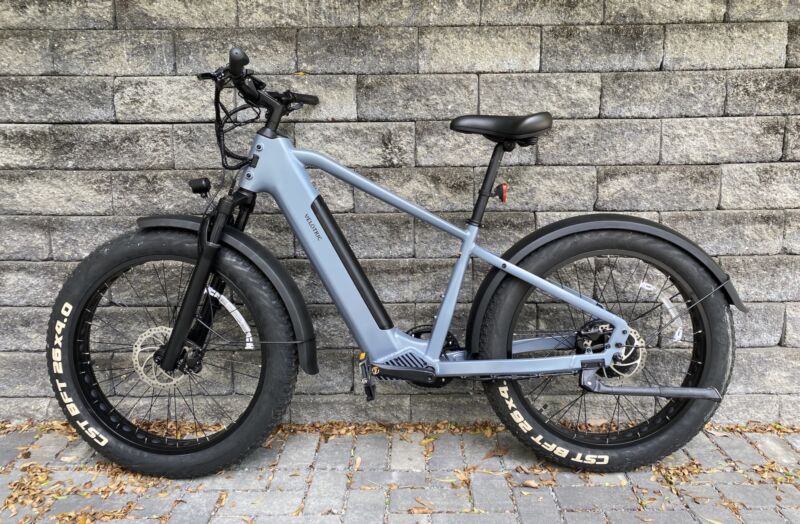 Image of a grey bike against a stone wall.