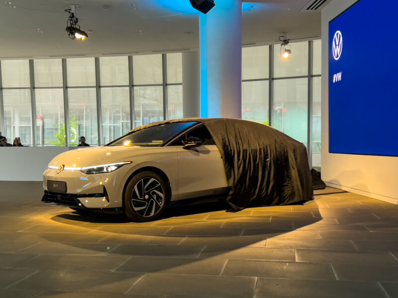 A car cover is pulled back to reveal the VW ID.7