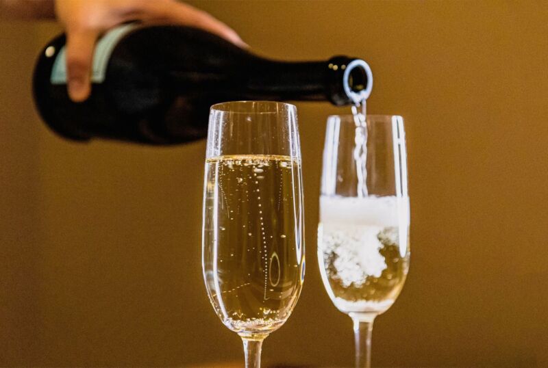 hand pouring champagne from a bottle into two fluted glasses
