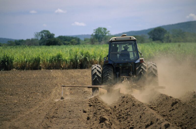 A tractor plowing a field, photographed from behind.