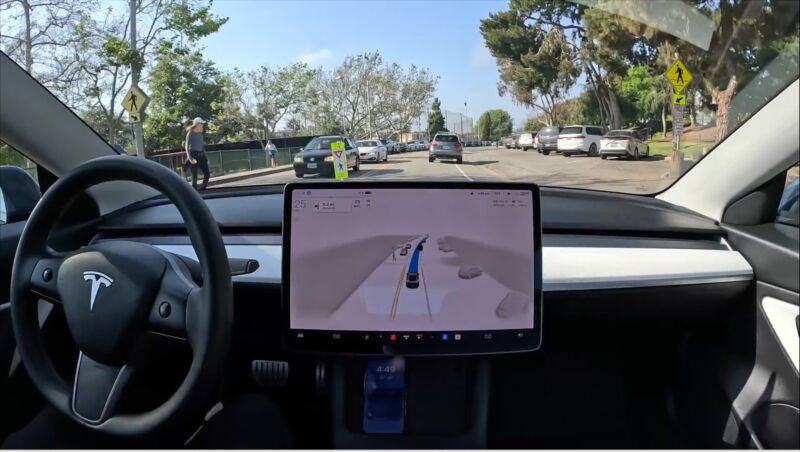 A screenshot of a video showing a Tesla detecting a pedestrian crossing at a crosswalk but not slowing down for them