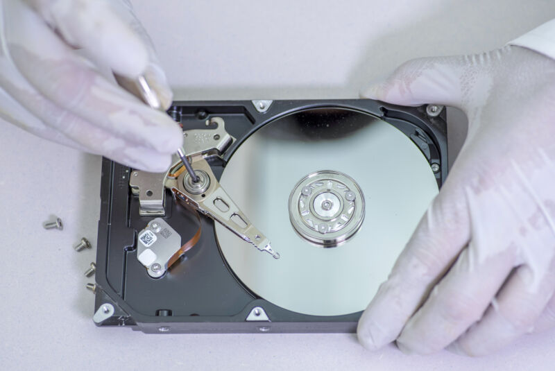 A technician repairing a hard disk drive with a tester
