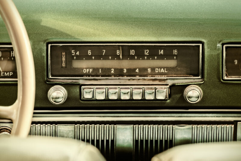 Retro style image of an old car radio inside a green classic car