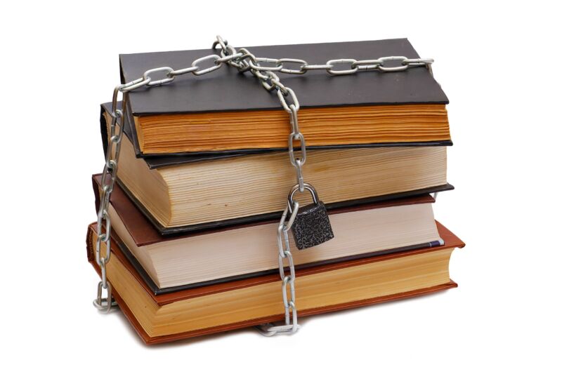 A stack of books wrapped in metal chains and locked with a padlock.